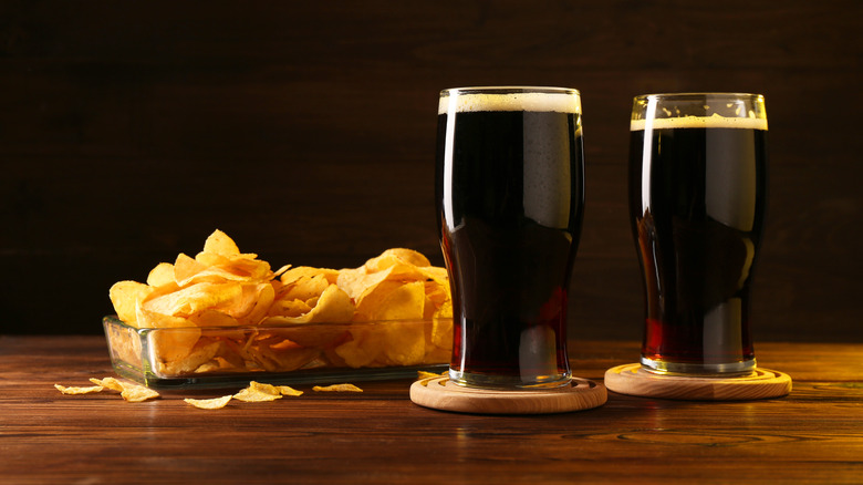 Glasses of beer and potato chips on wooden table