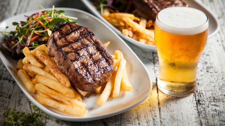 Grilled steak with fries, salad, and beer