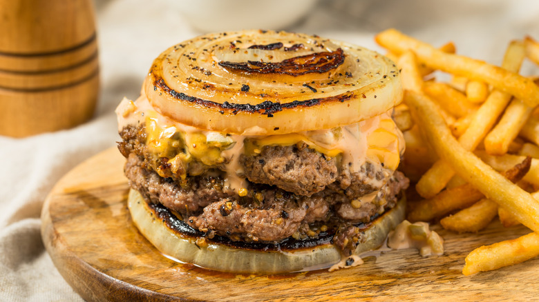 The Flying Dutchman from In-N-Out Burger sits next to a pile of fries on a wooden serving board