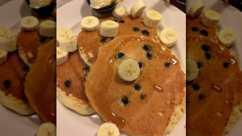 A plate of blueberry pancakes with sliced bananas at Perkins Restaurant & Bakery