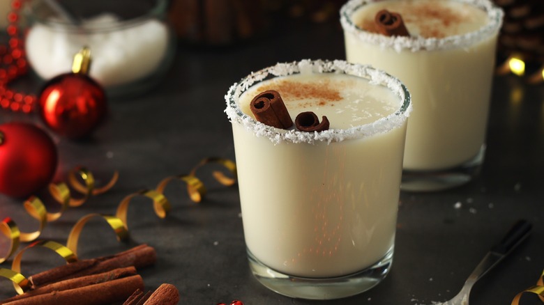 Two glasses of coquito with cinnamon sticks