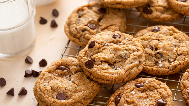 Chocolate chip cookies on a cooling tray beside a glass of milk