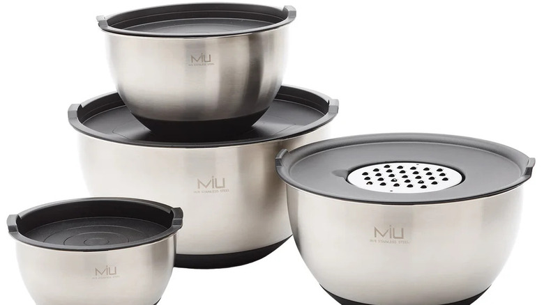 Stainless steel mixing bowl set with fitted lids and interchangeable grater attachment shown on a white background.