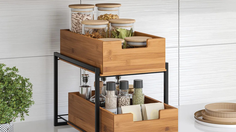 Two-tier bamboo countertop organizer with sliding drawers designed for storing spices, bottles, and small kitchen essentials.