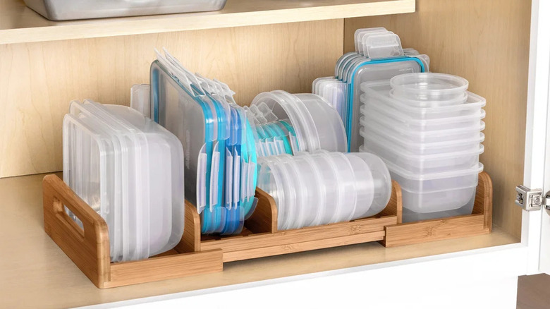 Expandable cabinet shelf organizer filled with Tupperware creating two storage levels.