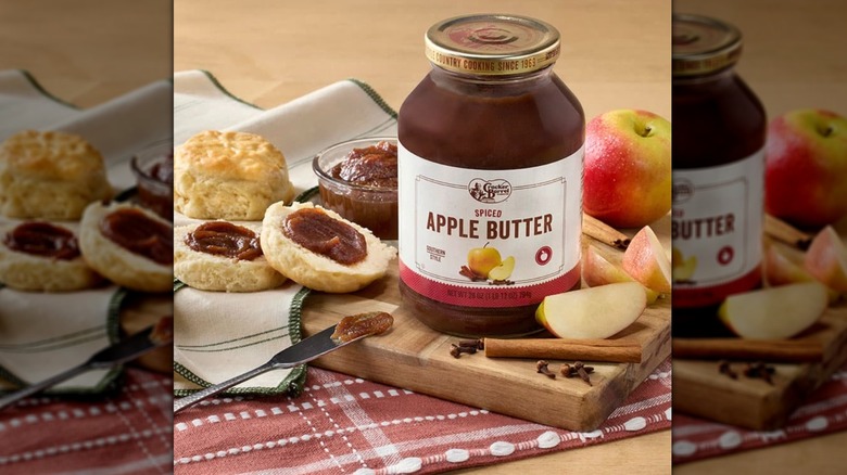 Jar of Spiced Apple Butter and its ingredients with spread on a split biscuit