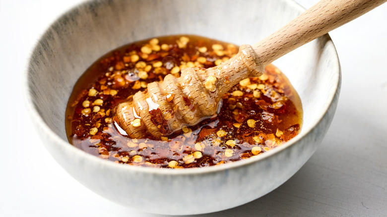 Bowl of hot honey with chili pepper flakes and a wooden utensil