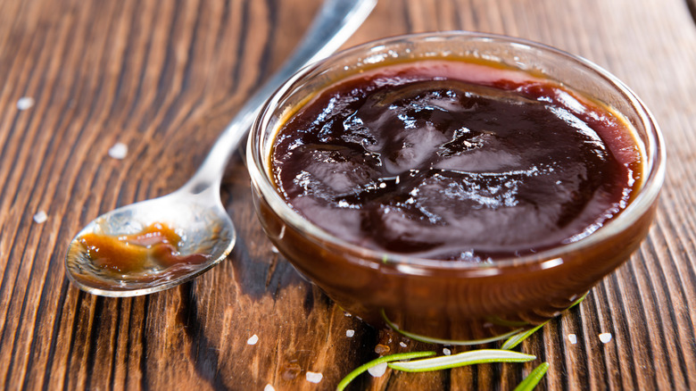 Barbeque Sauce with Tomatoes, Smoked Salt and fresh Herbs (on rustic wooden background)