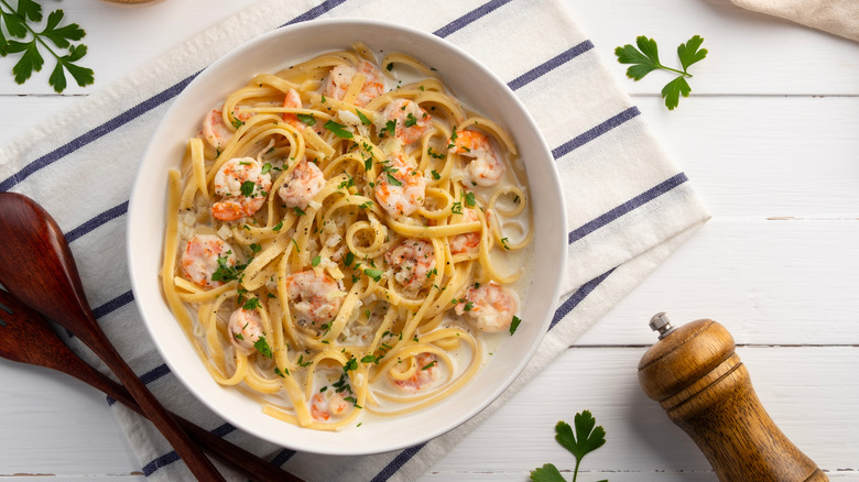 Fettuccine pasta with shrimp in white cream sauce.Creamy Shrimps Spaghetti carbonara sauce in white plate.Top view.