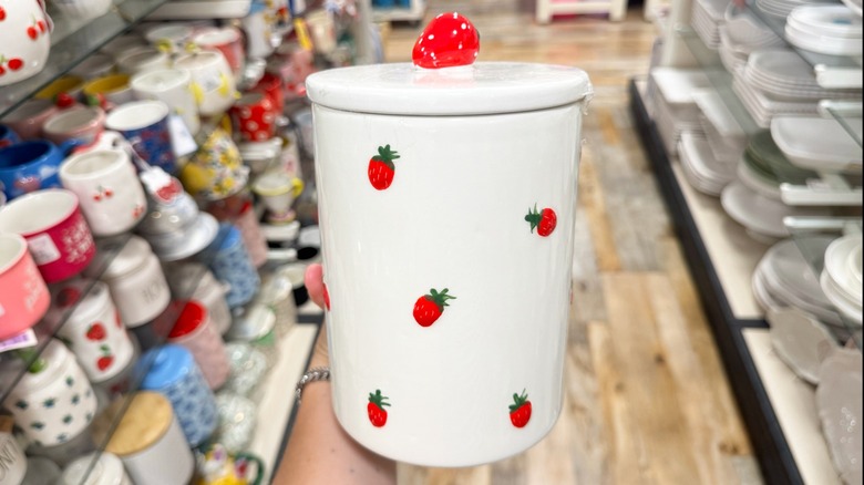 A white stoneware canister with strawberries painted on it
