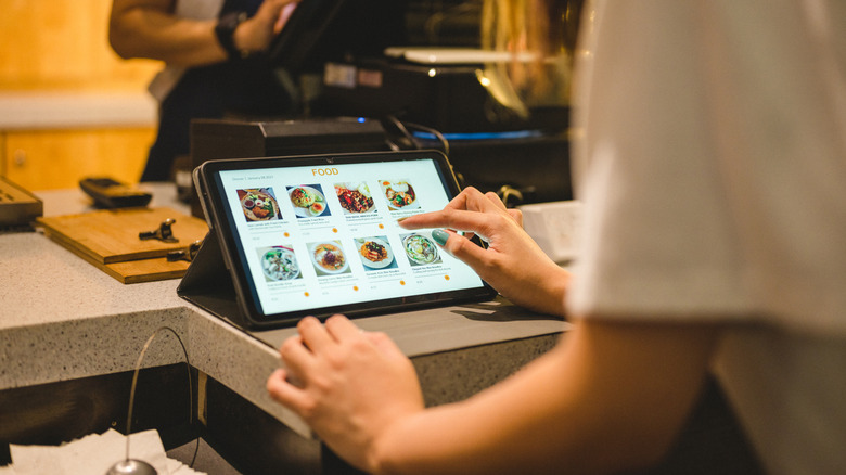 A server punches in a food order on a restaurant pay screen