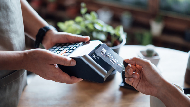 A  hand with a credit card paying a restaurant bill