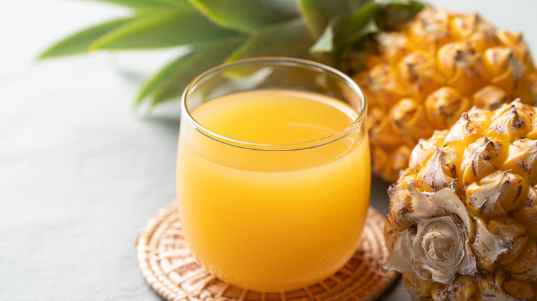 Pineapple juice alongside pineapples.