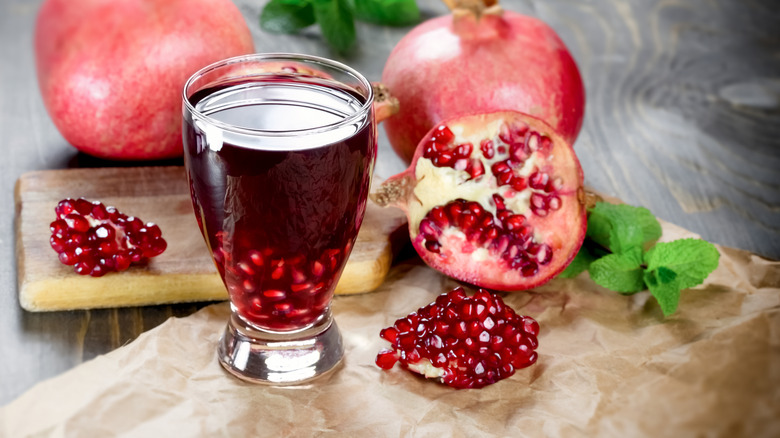 Pomegranate juice surrounded by fresh pomegranates.