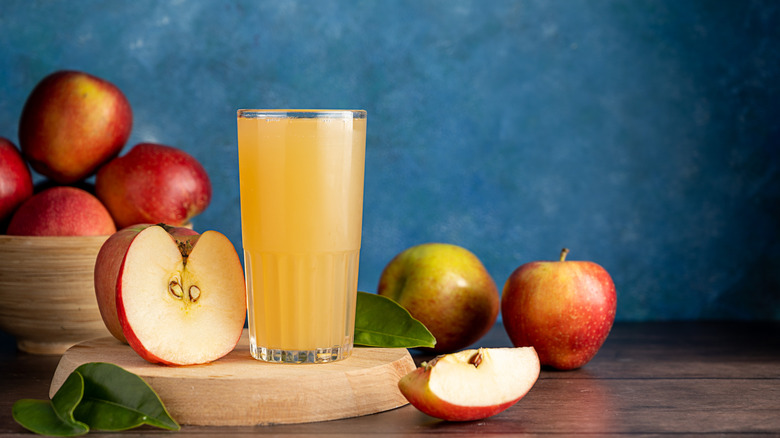 Pressed cider surrounded by apples.