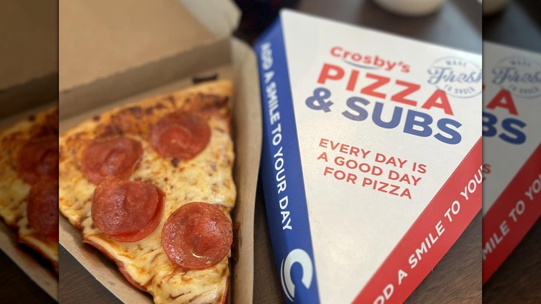 Slice of pepperoni pizza from Crosby's next to a cardboard container for another slice of pizza.