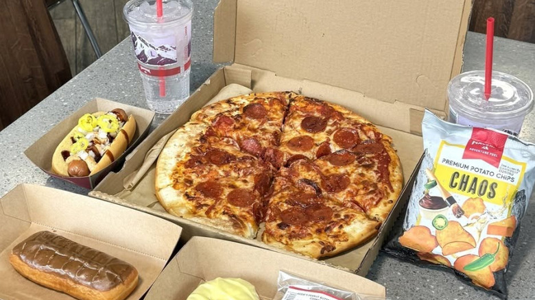 Pepperoni pizza flanked by loaded hot dog and premium potato chips, alongside two cups of water and a chocolate dessert from Maverik.