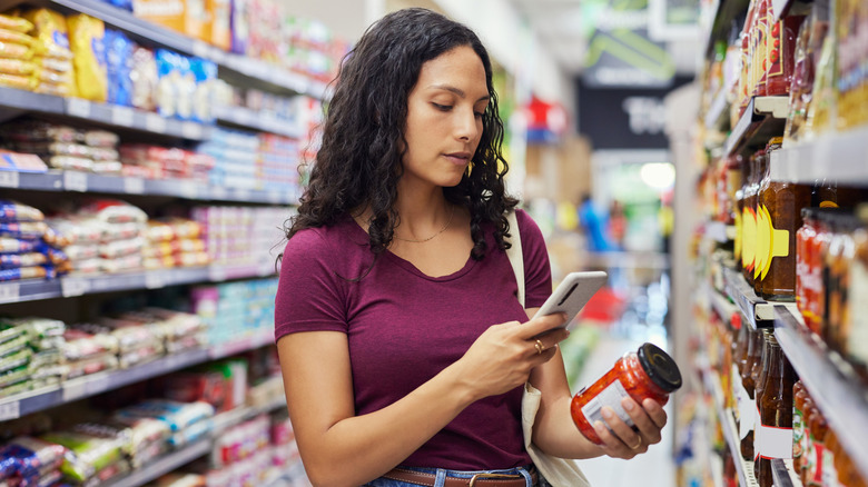 Woman using smartphone to scan a jar in the grocery store