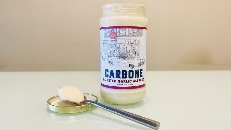 Open jar and spoonful of Carbone Roasted Garlic Alfredo Sauce
