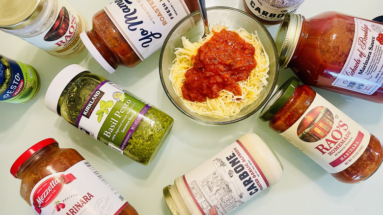 Various store-bought pasta sauce jars with bowl of spaghetti