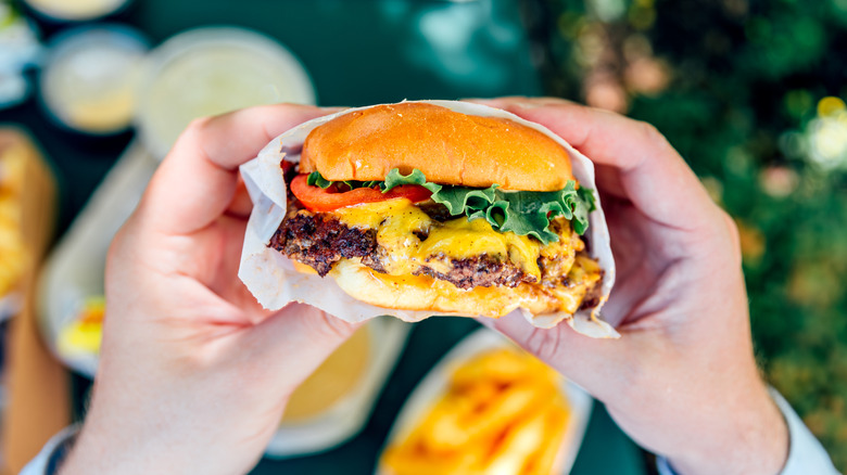Hands holding fast food burger in wrapper