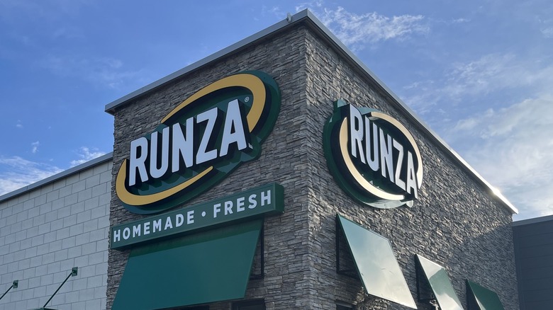 Green, yellow, and white Runza logo on a brick storefront