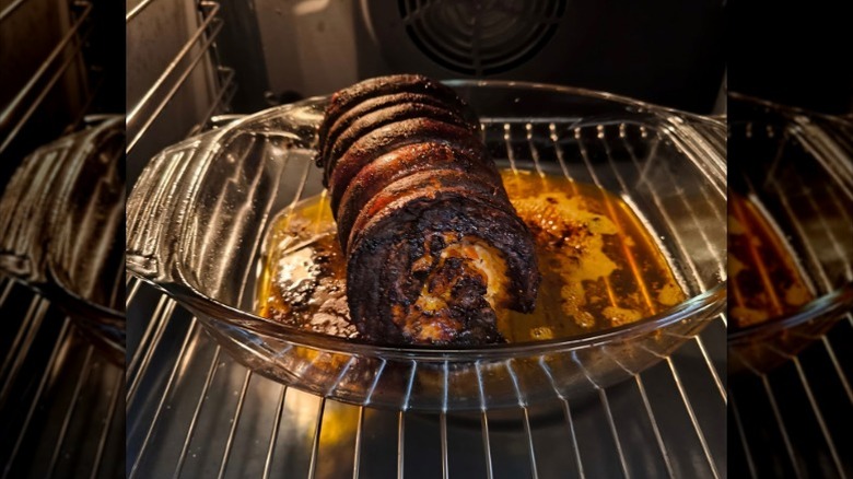 A burned port roast sits in a glass dish inside an oven
