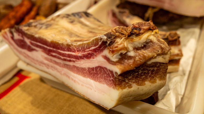 A rack of pork ribs dries in a plastic container lined with paper towels