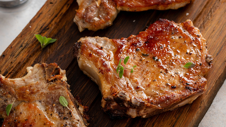 Seared pieces of pork rest on a wooden cutting board