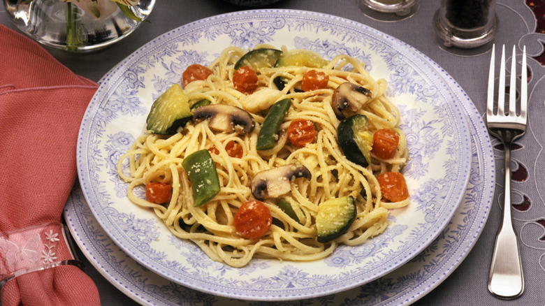 vintage pasta primavera on a blue and white plate with a fork and red napkin
