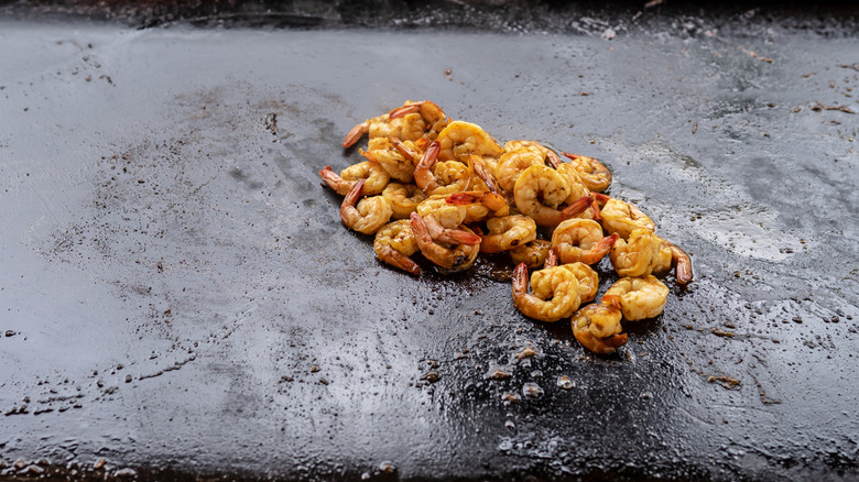 A pile of shrimp is cooked on an oiled Blackstone Griddle