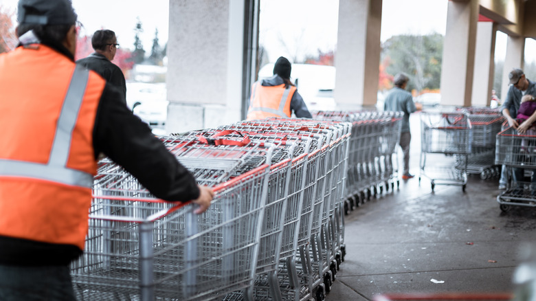 Costco attendants return loads of carts to the front of a warehouse