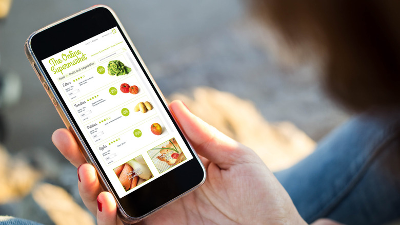 Person holding phone and grocery shopping online