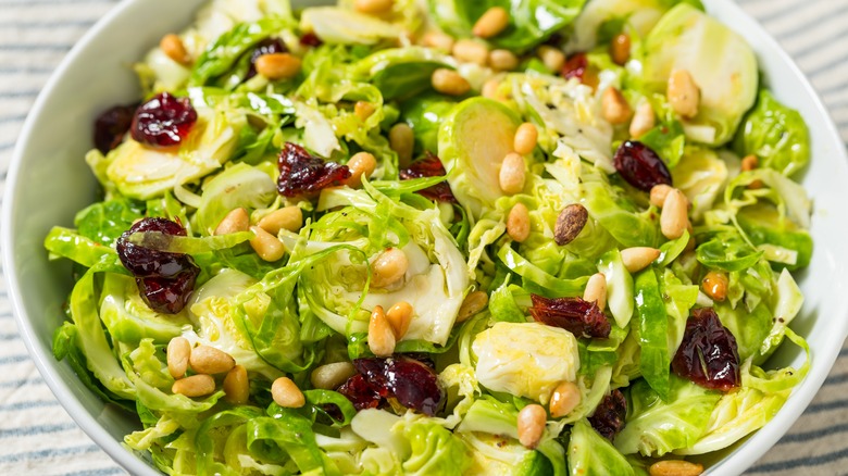 White bowl full of Brussels sprouts with pine nuts and craisins