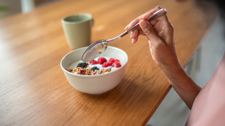 woman eating oatmeal with fruit and granola