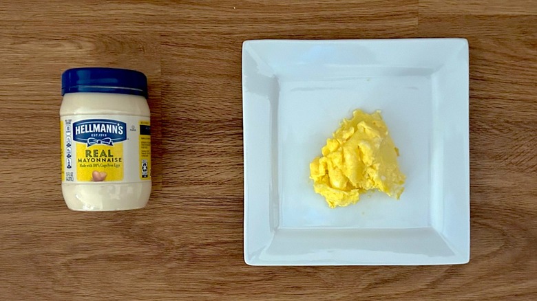 Jar of Hellmann's mayonnaise and square white plate of scrambled eggs