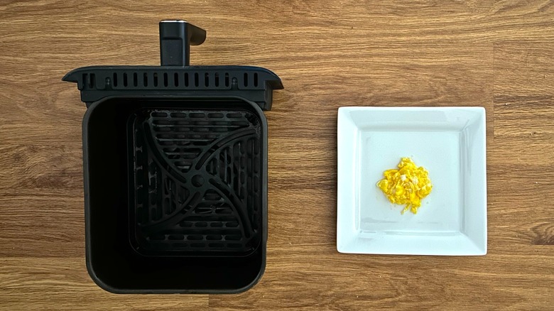 Air fryer basket and square white plate of scrambled eggs