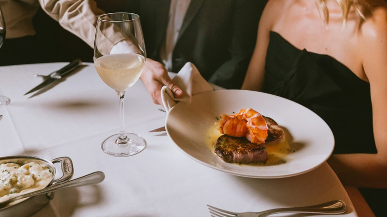 A waiter sets a plate of food on a table.