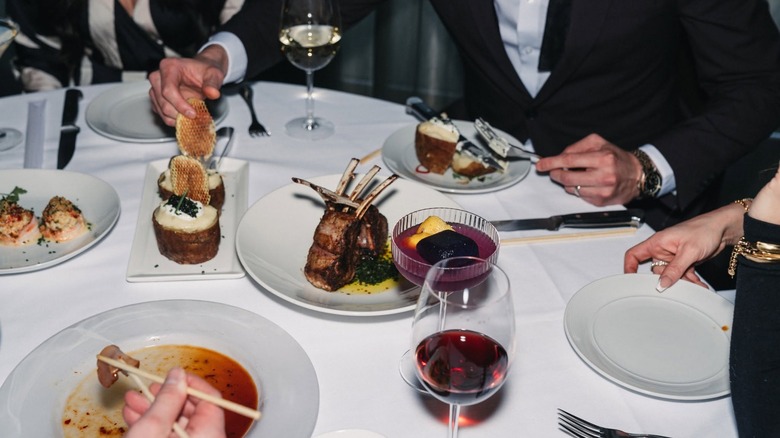 Finely plated foods and cocktails sit on a restaurant table.
