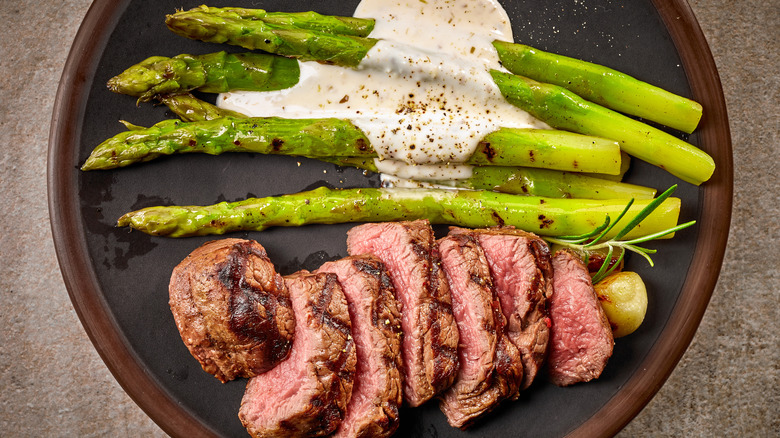 Sliced steak with asparagus in creamy sauce