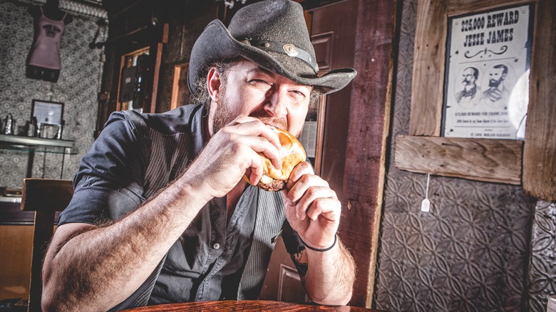 A cowboy eating a burger