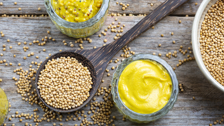 Two kinds of mustard and mustard seeds on wood table