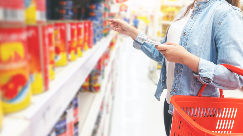 woman shopping for canned tomatoes at grocery store