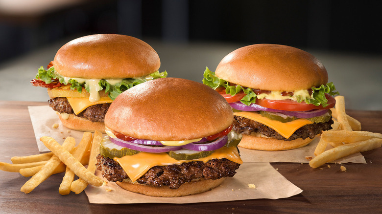 Jollibee's three new 100% certified angus beef hamburgers are pictured together along with some scattered french fries