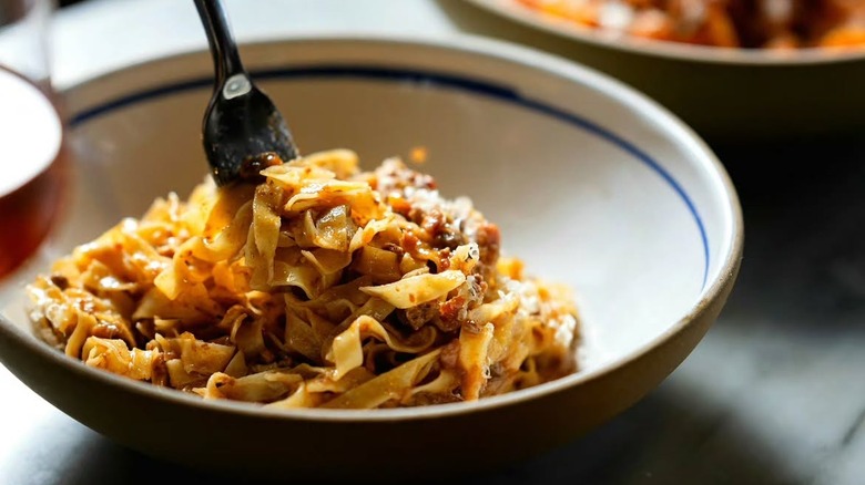 bowl full of tagliatelle bolognese pasta with a fork in it