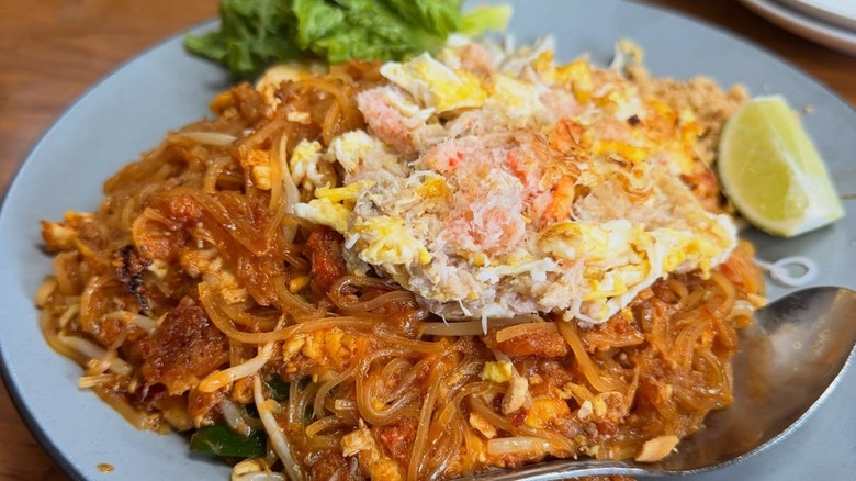close up of thai noodle dish on a plate with crab on top