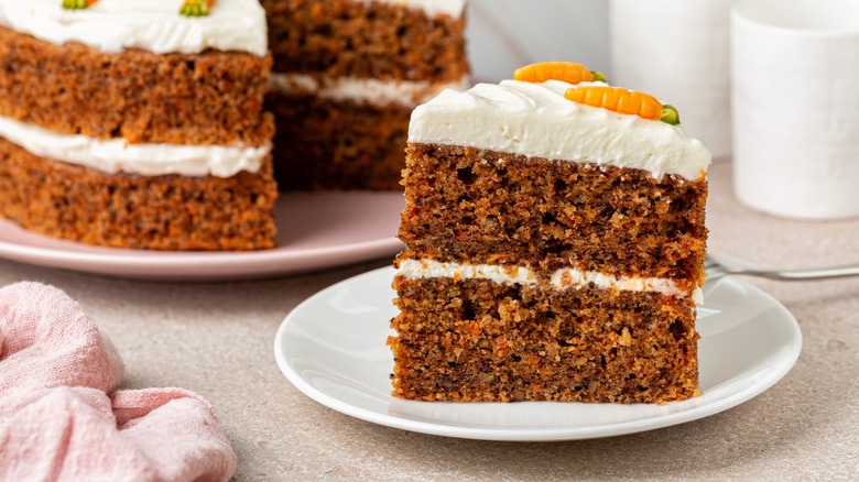 A layered carrot cake with a slice set aside on a plate