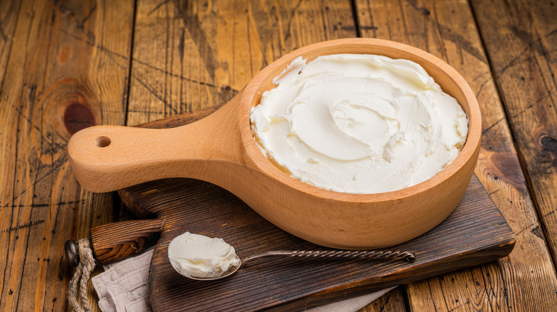 A wooden bowl full of creamy mascarpone cheese.