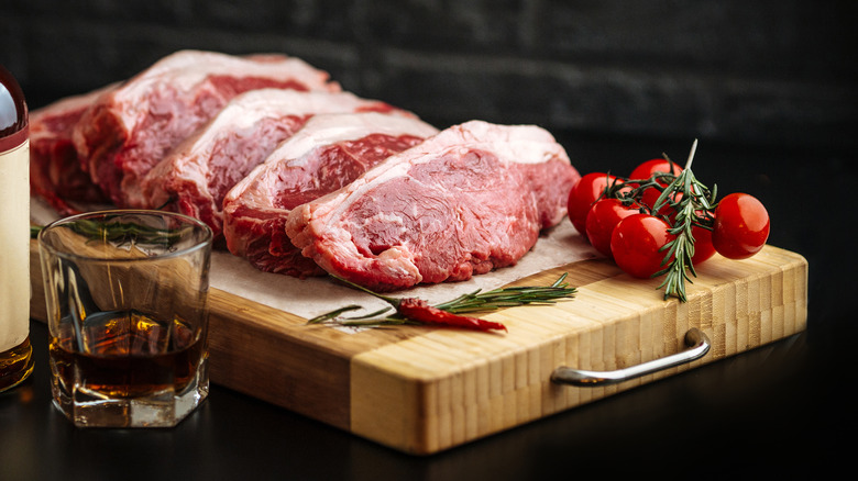Raw steaks with bottle and glass of bourbon