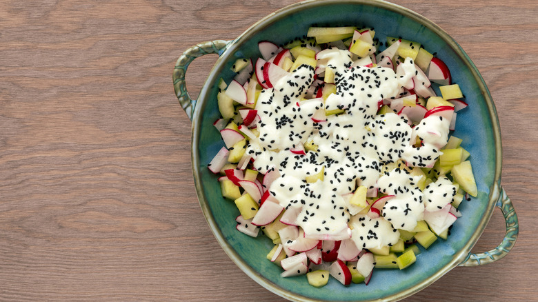 Salad bowl with cucumber, radishes, and nigella seeds